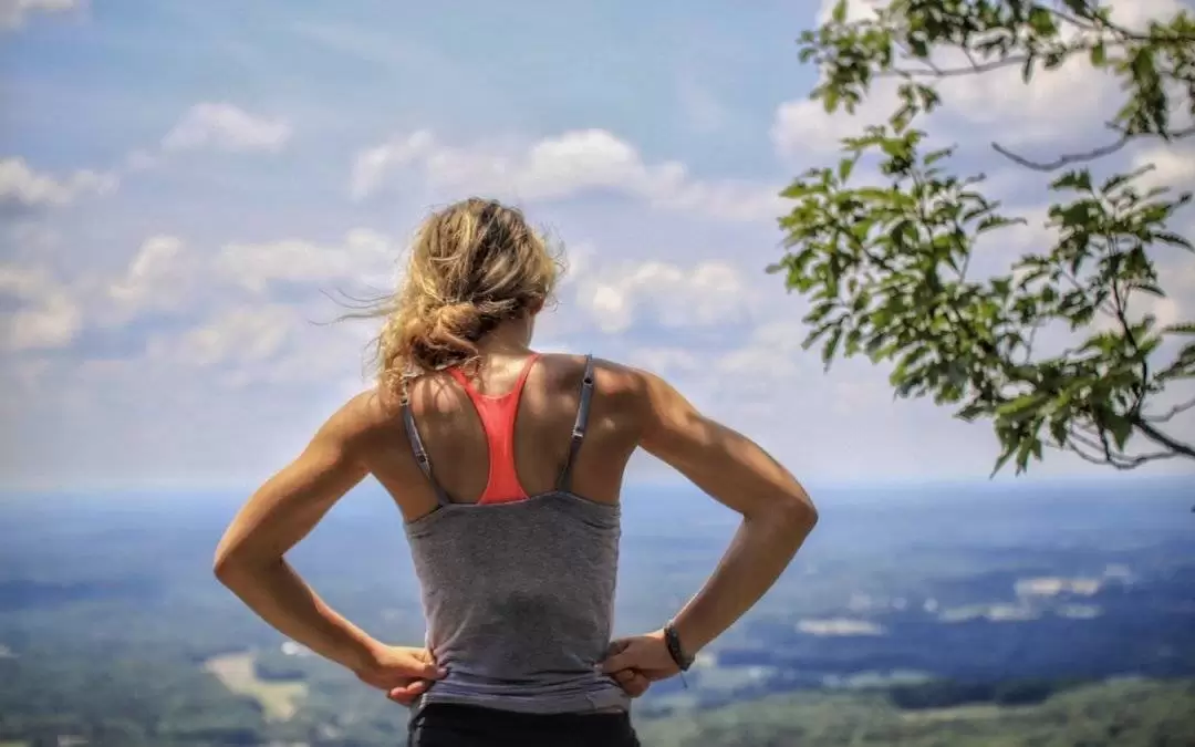 Woman in workout gear stood on mountain looking out over landscape