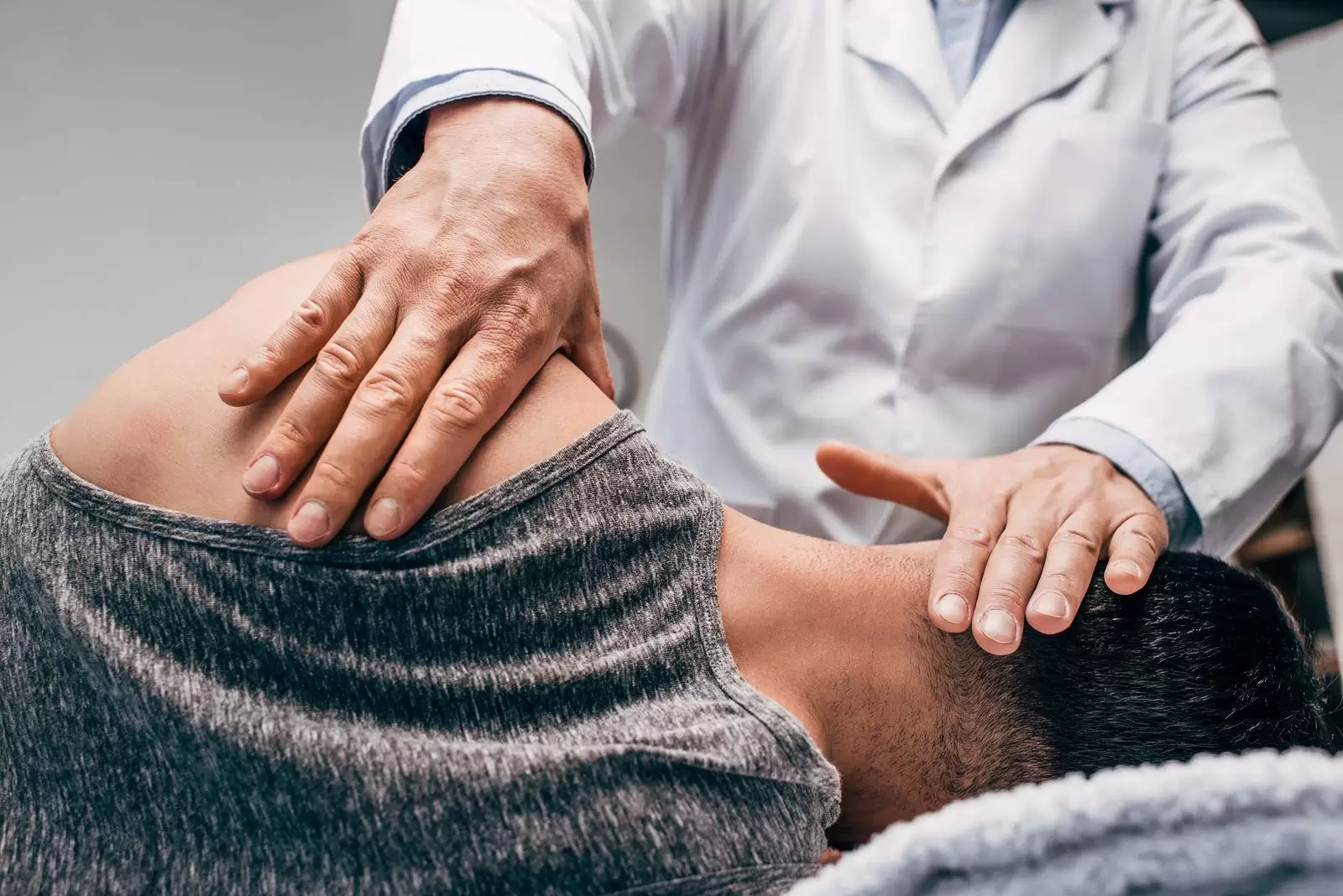 Chiropractor massaging shoulder of man lying on side