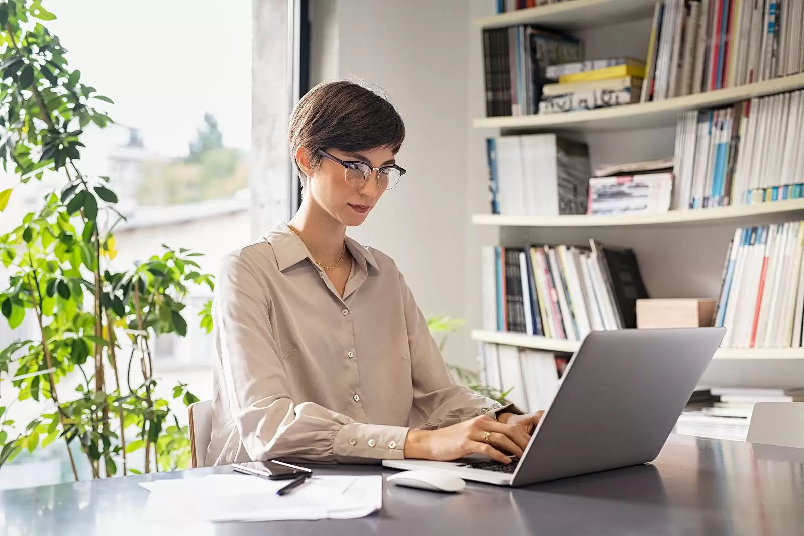 Young businesswoman sitting on her workplace in the office and working on laptop. Creative young woman using computer in meeting room. Business woman entrepreneur working from home in smart working.